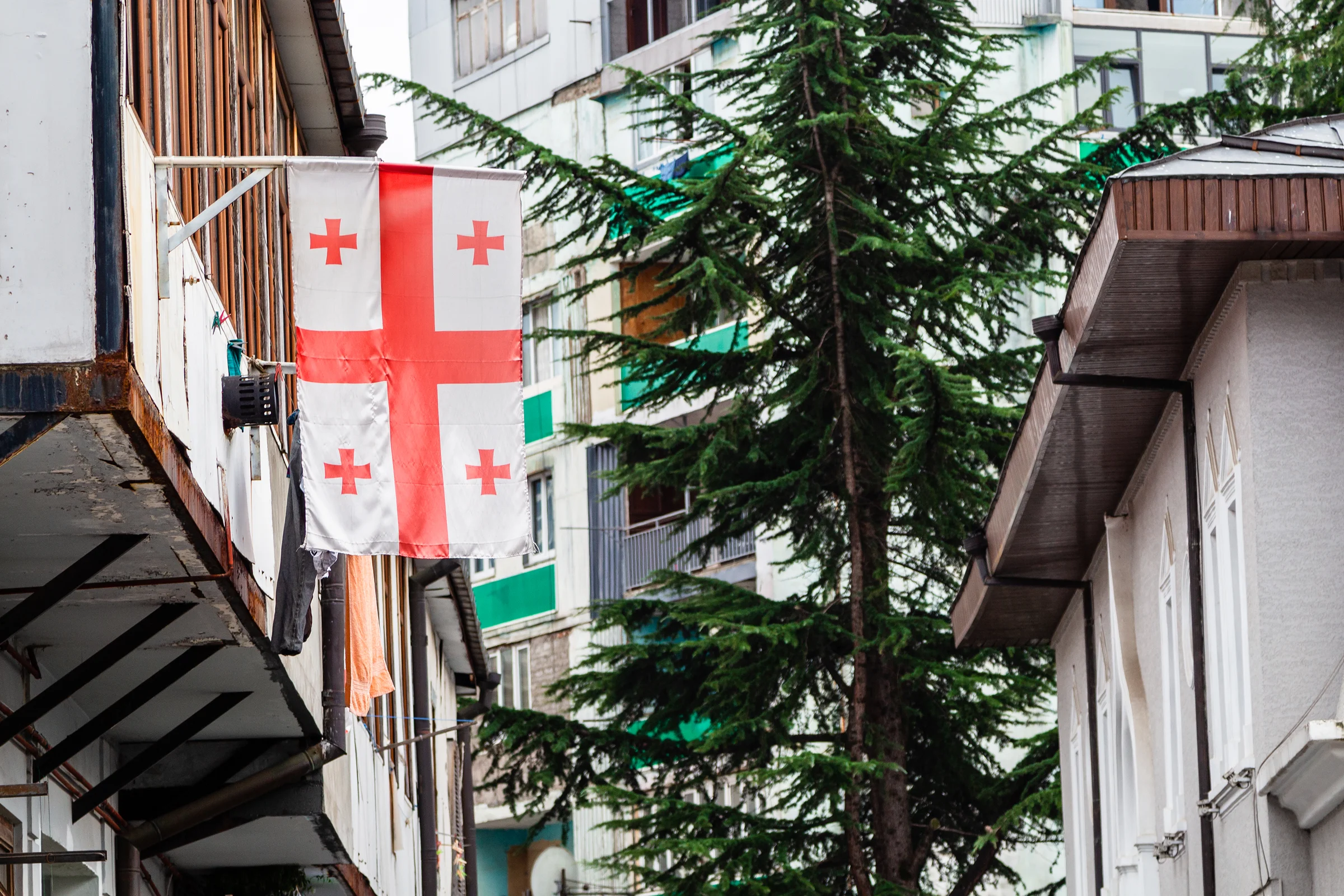 Georgian flag hanging from a traditional balcony on a residential building in Tbilisi