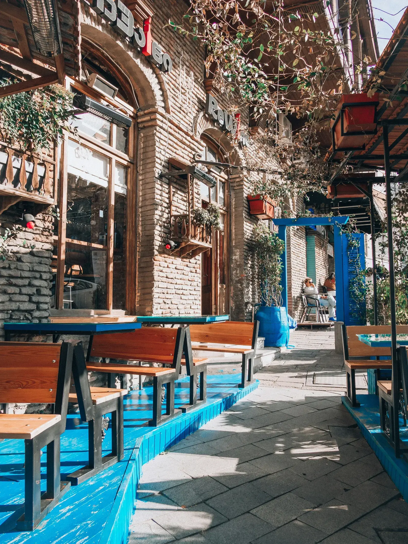Cozy outdoor café terrace on a cobblestone street in Tbilisi with blue-painted furniture