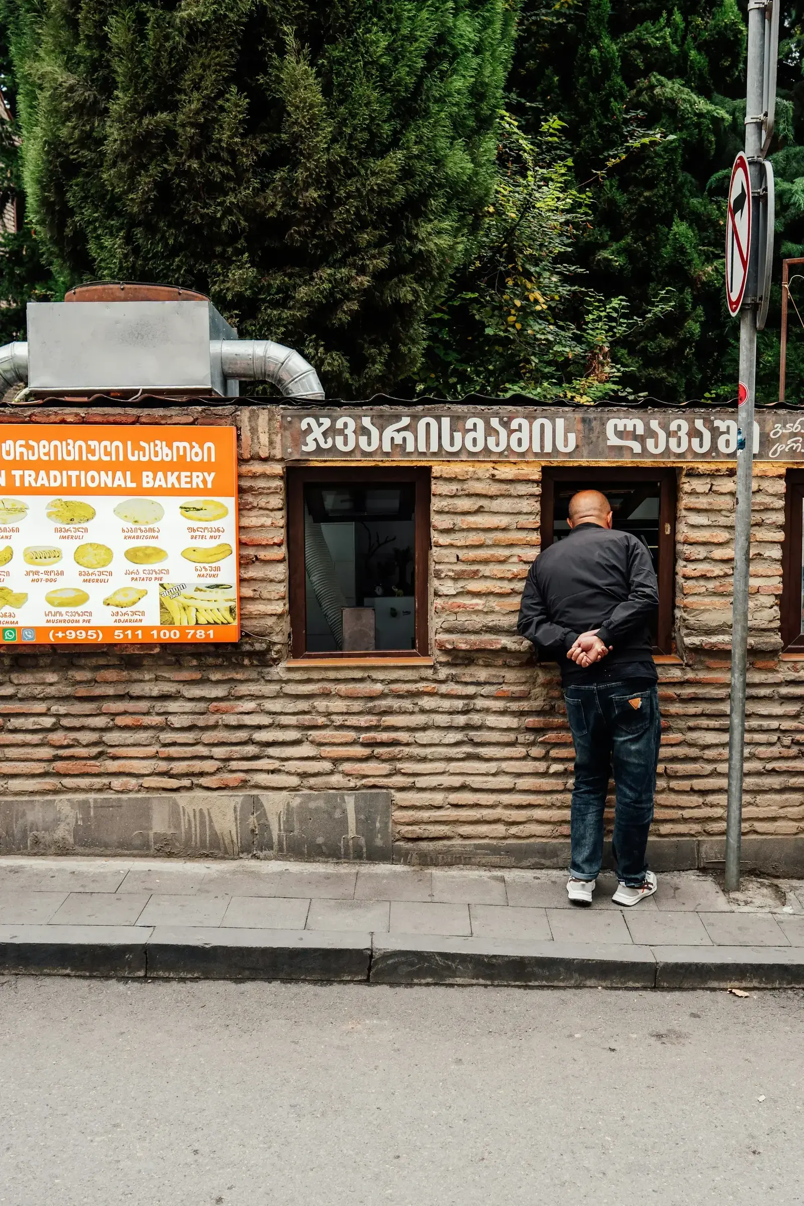 A man looking at a traditional Georgian bakery storefront in Tbilisi with Georgian script signage