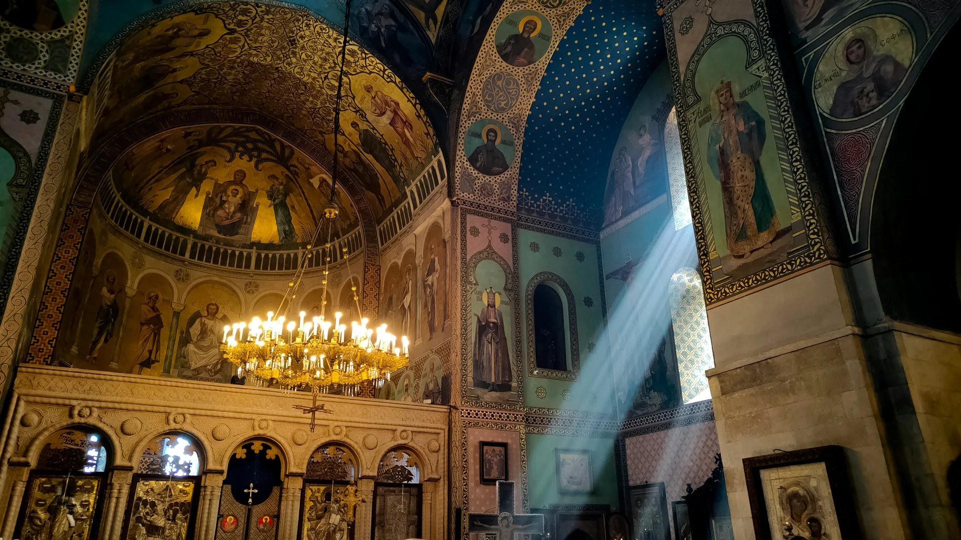 Interior of a Georgian Orthodox church with Byzantine frescoes and golden chandeliers