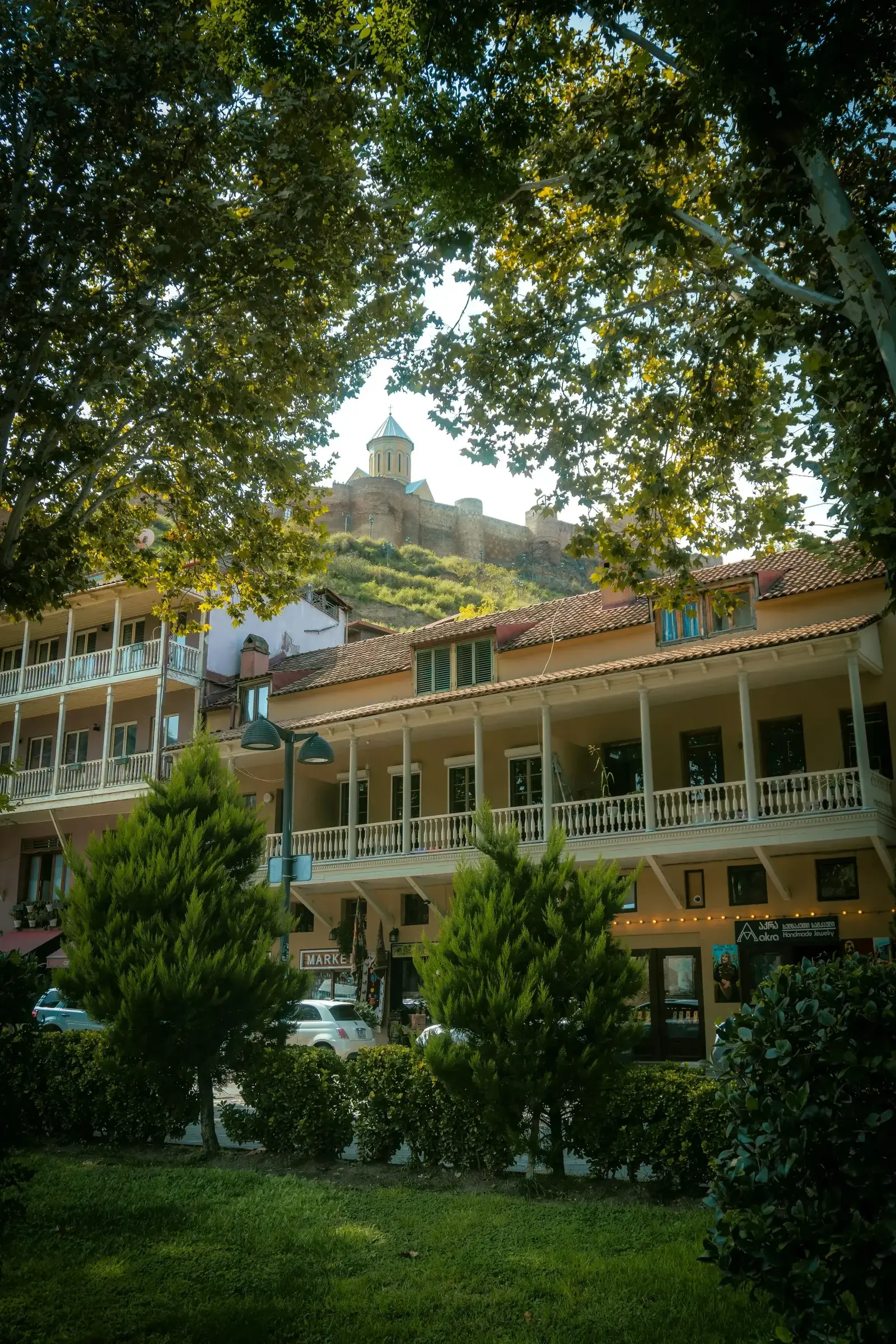 Charming Old Town Tbilisi with traditional balconies, shops, and Narikala Fortress on the hilltop