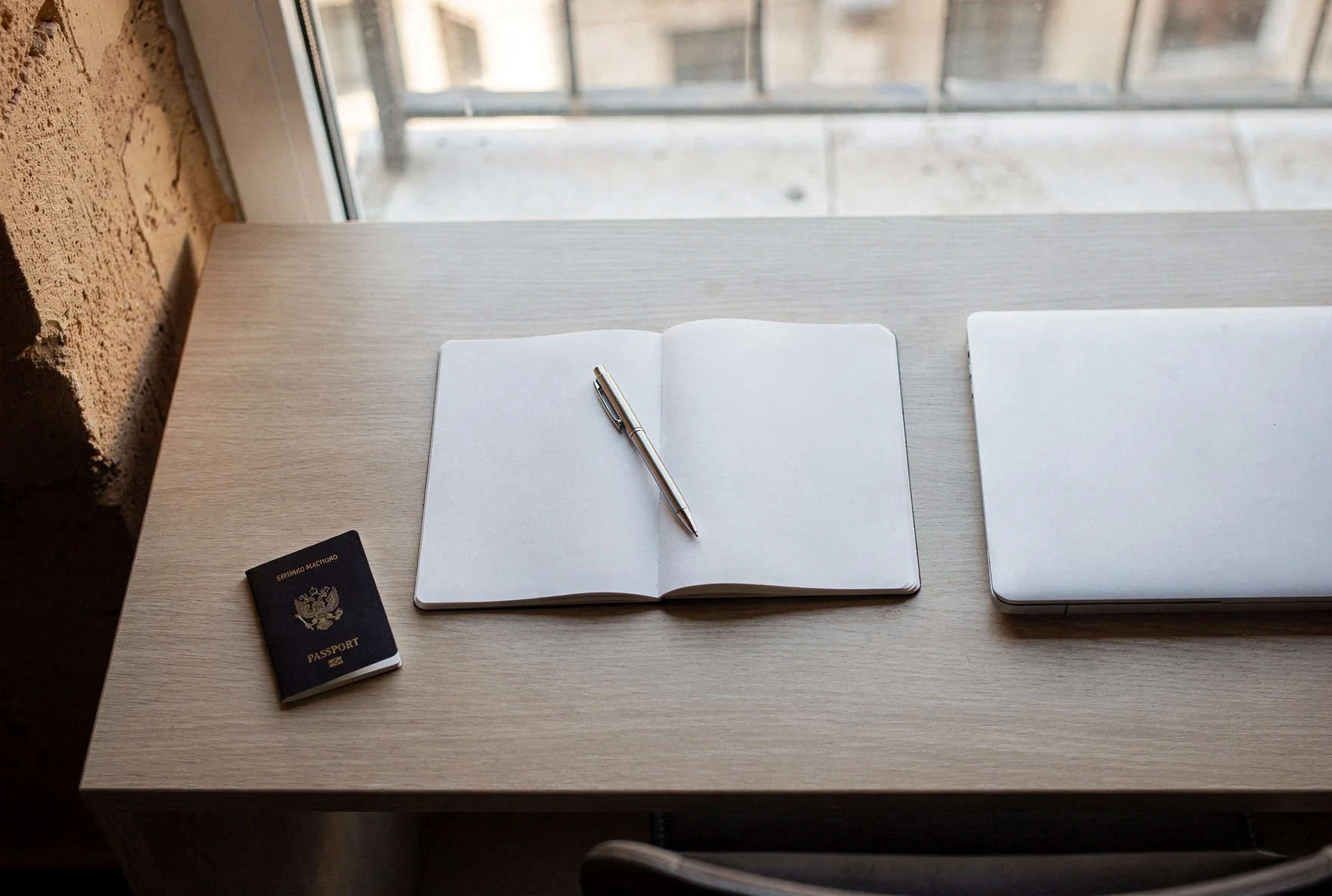 Passport and notebook next to a laptop on a tidy desk before starting government registration