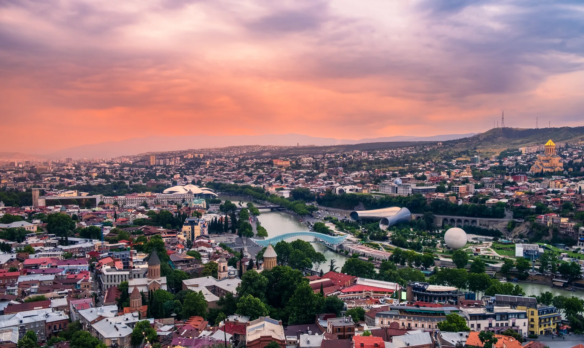 Panoramic view of Tbilisi at sunset with the Bridge of Peace and Holy Trinity Cathedral