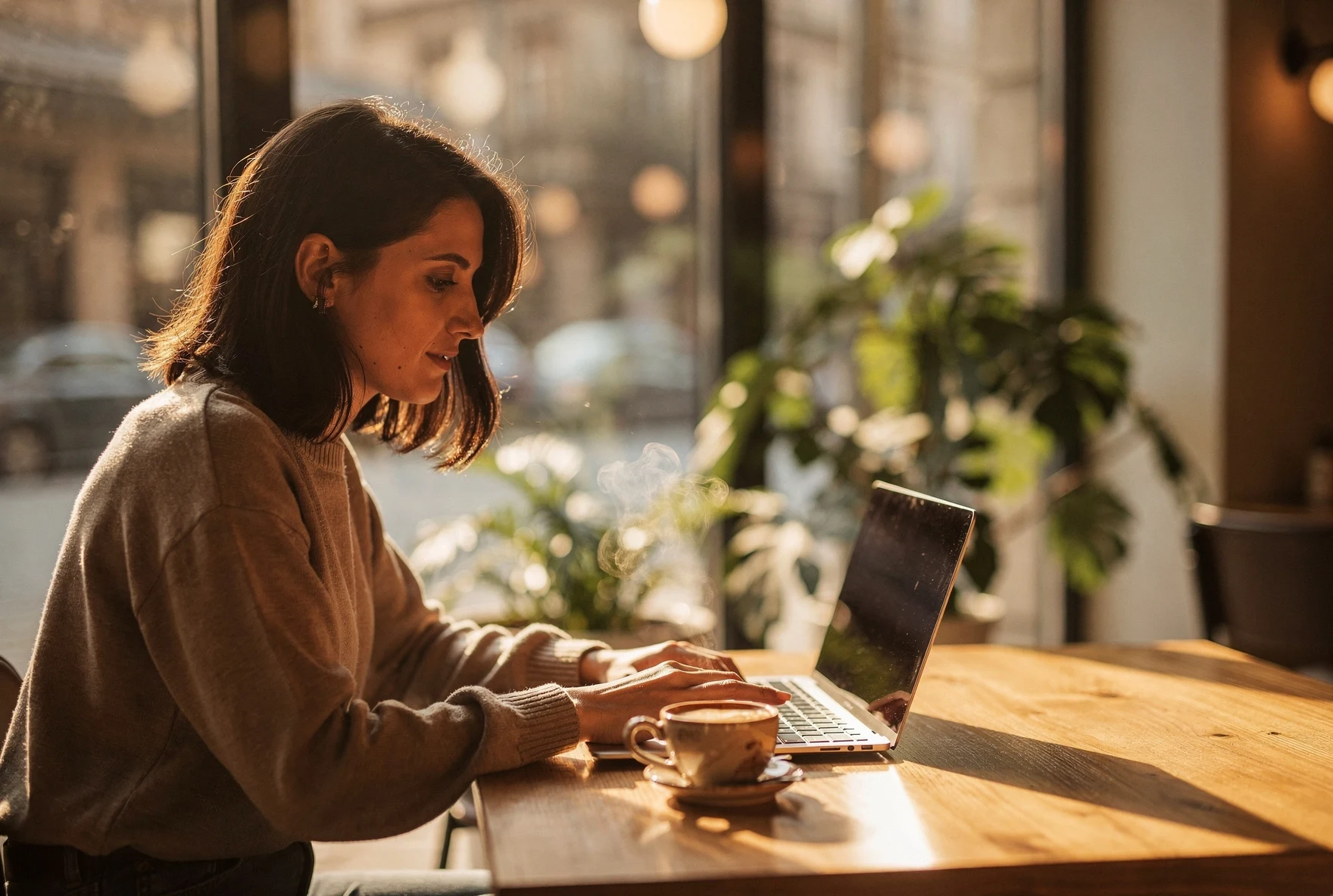 Woman working on laptop in a cozy Tbilisi cafe with warm lighting